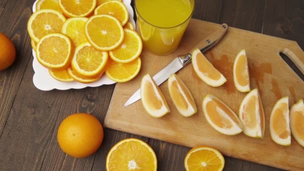 木製のテーブルの上に新鮮なオレンジの果物 全体とスライス 柑橘類のスライスでいっぱいのプレート — ストック動画