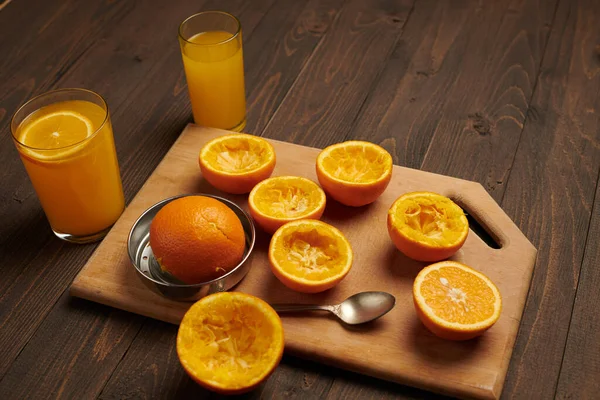 Fresh orange fruits whole and squeezed on a wooden table, cutting board - natural and healthy food. Glass of fruit cocktail.