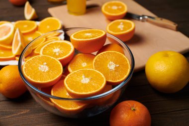 Taze portakal meyvesi ve ahşap bir masada dilimlenmiş tahta ve mutfak bıçağı. Turunçgil dilimleriyle dolu bir tabak. Doğal ve sağlıklı yiyecek. Bir bardak meyve kokteyli..