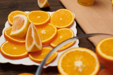 Taze portakal meyvesi ve ahşap bir masada dilimlenmiş tahta ve mutfak bıçağı. Turunçgil dilimleriyle dolu bir tabak. Doğal ve sağlıklı yiyecek. Bir bardak meyve kokteyli..