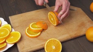 Mutfak kesim tahtasında portakal meyvesi dilimlemek, arka plan olarak ahşap masa, yakın görüş..