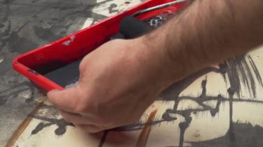 Ahşap arka planda soyut bir resim, grunge tarzı ölüm, kontrplak üzerindeki koyu boya, bir adamın eli fırça ya da silindir kullanır.