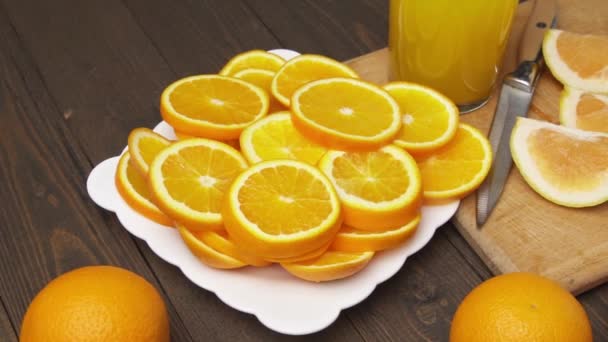 木製のテーブルの上に新鮮なオレンジの果物 全体とスライス 柑橘類のスライスでいっぱいのプレート — ストック動画
