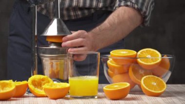 Manüel baskı ile portakal meyvesi sıkmak, yakın görüş, bir bardak taze şarap yapmak. Tahta bir masada taze portakallar, bütün ve dilimlenmiş..