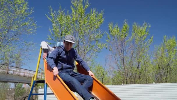 Niños Jugando Deslizándose Patio Recreo Junto Condominio Columpio Tobogán Escaleras — Vídeo de stock