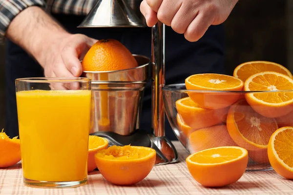 用手动压榨机挤压橙子 近距离观察 做成一杯新鲜的 木制桌子上新鲜的橙子 完整的 挤压的和切片的 — 图库照片