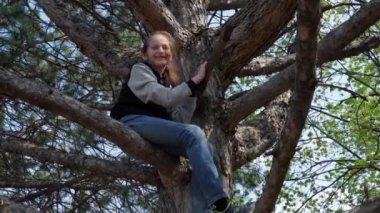 Küçük kız ağaca tırmanıyor, parlak güneş ışığı, güzel bir gün.