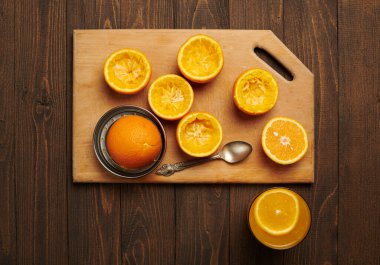 Taze portakal meyveleri ve ahşap bir masaya sıkıştırılmış, tahtayı kesiyor - doğal ve sağlıklı yiyecekler. Bir bardak meyve kokteyli..