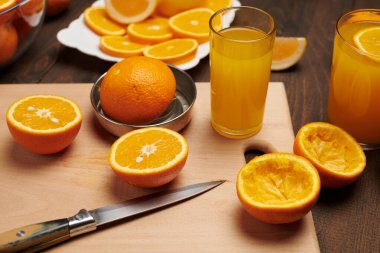 Taze portakal meyvesi ve ahşap bir masada dilimlenmiş tahta ve mutfak bıçağı. Turunçgil dilimleriyle dolu bir tabak. Doğal ve sağlıklı yiyecek. Bir bardak meyve kokteyli..