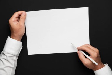 boş bir kağıt ve siyah bir masa üzerinde bir işadamı elleri, beyaz bir gömlek ve bir kol saati, herhangi bir yazı veya yazı için üst görünüm şablonu