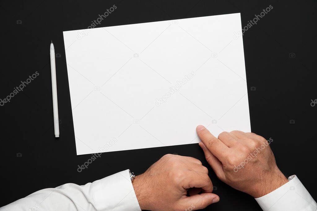 a blank sheet of paper and a businessman's hands on a black table, a white shirt and a wrist watch, a top view-a template for any text or inscription