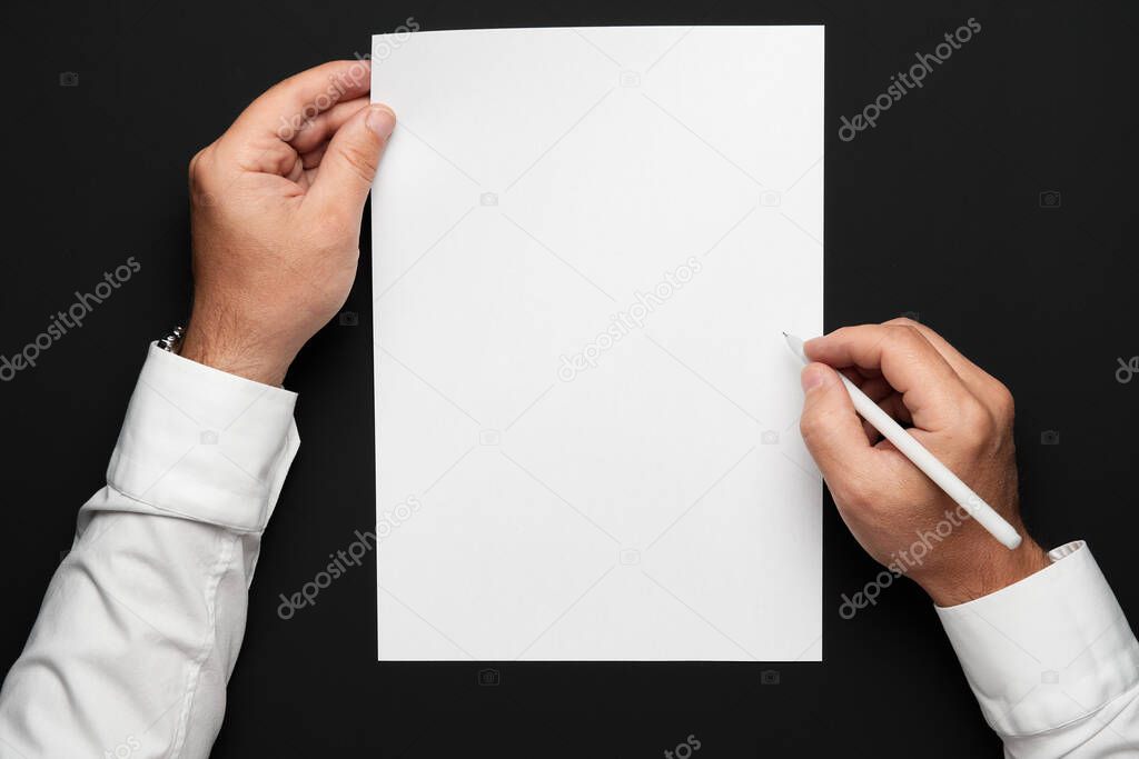 a blank sheet of paper and a businessman's hands on a black table, a white shirt and a wrist watch, a top view-a template for any text or inscription