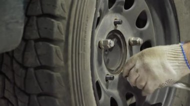 Bir araba tekerleğini değiştirmek, bir garajda vida sökmek ve vidaları vidalamak.