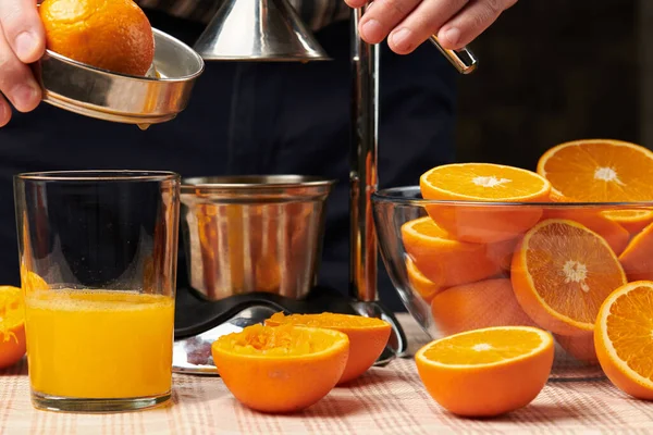 用手动压榨机挤压橙子 近距离观察 做成一杯新鲜的 木制桌子上新鲜的橙子 完整的 挤压的和切片的 — 图库照片