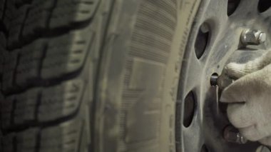 Bir araba tekerleğini değiştirmek, bir garajda vida sökmek ve vidaları vidalamak.