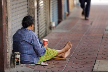 Thai woman begging in Bangkok street clipart