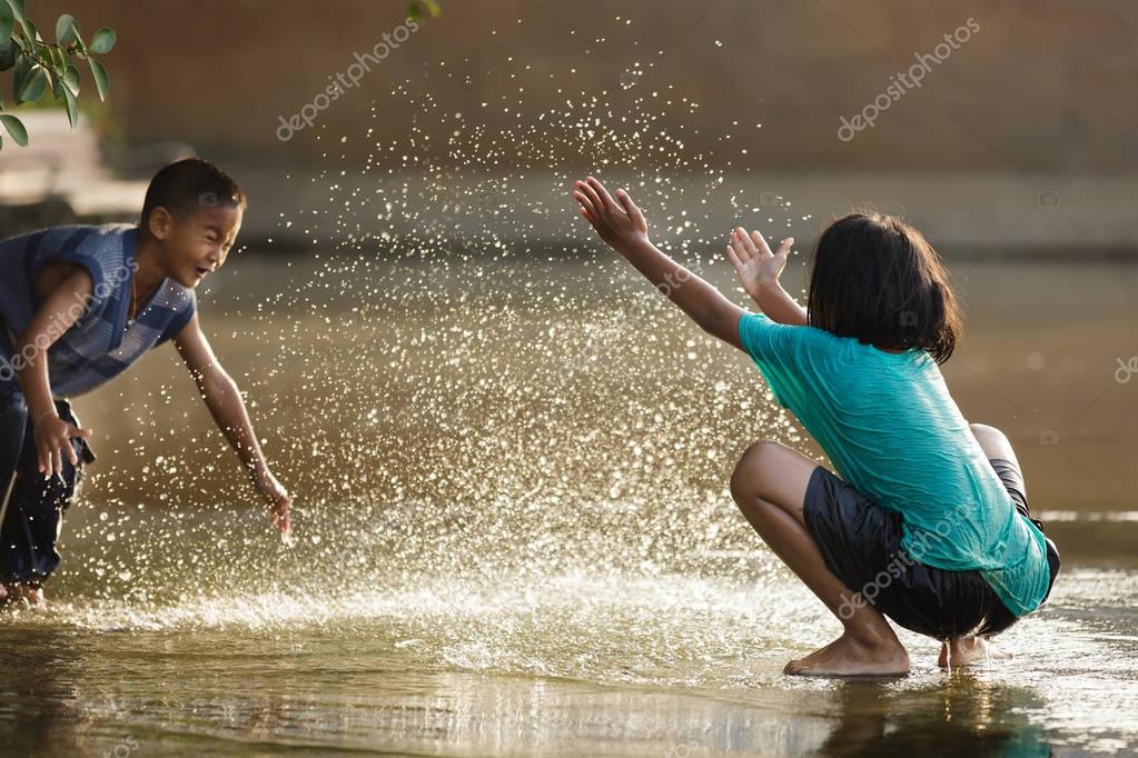 Child Playing In The Water In The Sand Wearing Blue Hi Res Stock