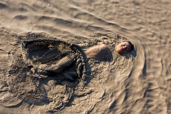 Young boy fisdhing in muddy water — Stock Photo, Image