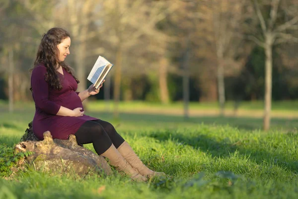 Femme enceinte lisant un livre en plein air — Photo