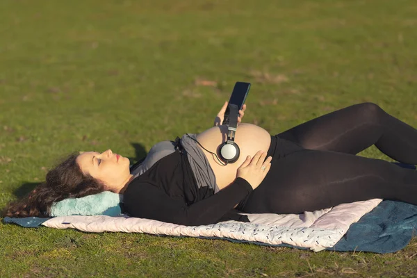 Femme enceinte avec écouteurs sur le ventre — Photo