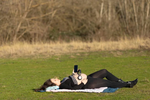 Mujer embarazada con auriculares sobre su vientre — Foto de Stock