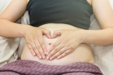 Kalp şekli hamile karnına tabelada eller