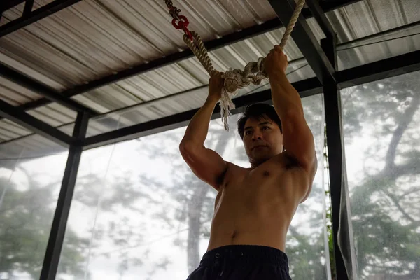 Asian muscled man training trx