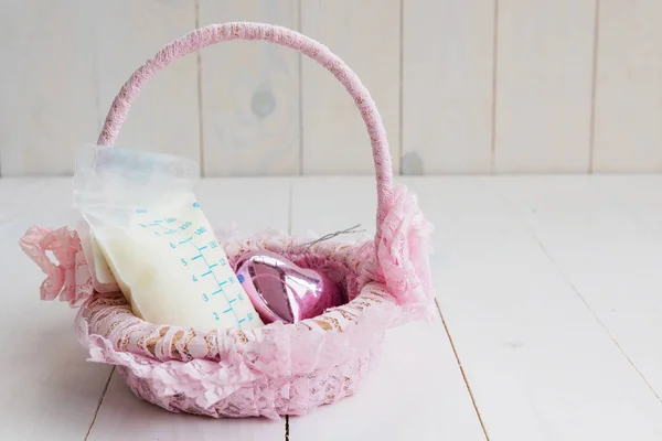 Breastmilk on pink basket with wood background