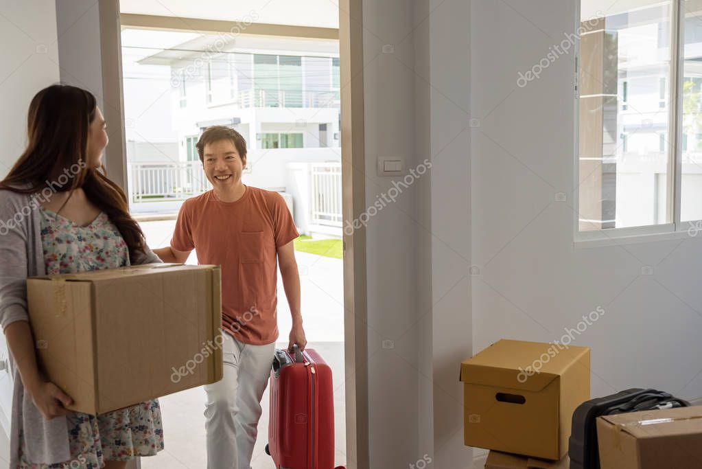 Couple carry moving boxes and luggage to new house