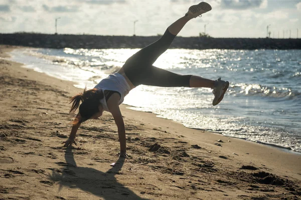Female somersault on beach at sunrise — Stock Photo, Image