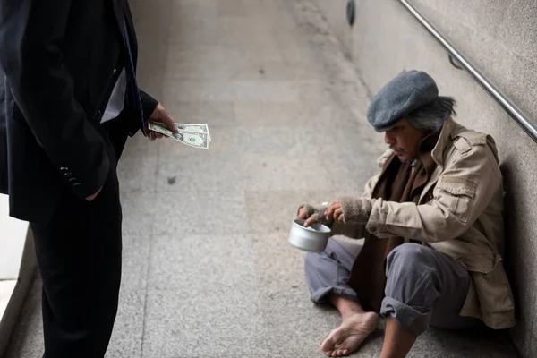 Działalności człowieka dać pieniądze do bezdomnego — Zdjęcie stockowe
