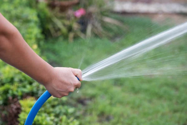 Spray water to grass yard by rubber hose — Stock Photo, Image