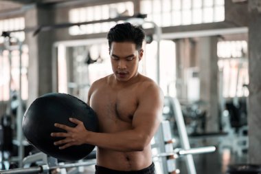 Spor salonunda kaslı bir adam karın ağrısı egzersizi yapıyor.