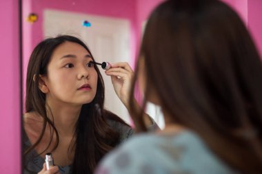 Kadınlar aynada kirpik yaparlar.