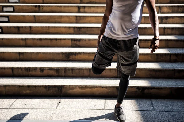 Negro africano homem alongamento perna antes de correr — Fotografia de Stock