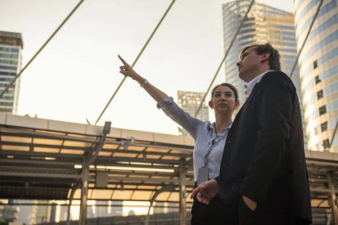Kadın işçi, modern yapıyı işaret ediyor ve iş inşaatı projesini gün batımında tartışmak için Amerikalı iş adamının patronuna bakıyor. Emlak endüstrisi