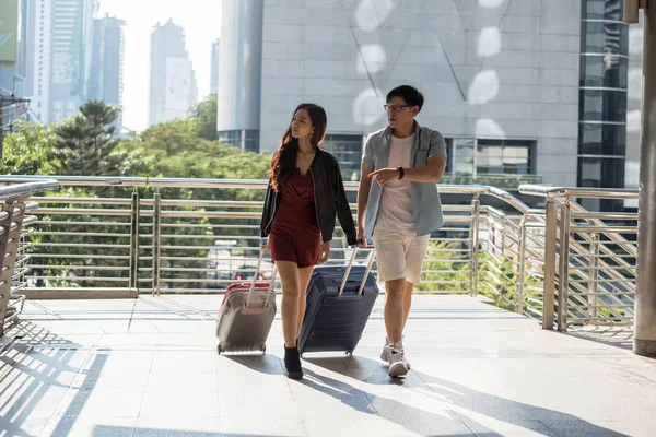 Azji para spacer i ciągnąć dwa bagaże podróżne w mieście — Zdjęcie stockowe