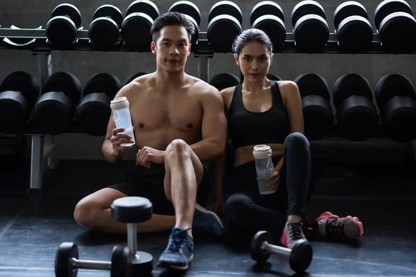 couple break and drink water in gym