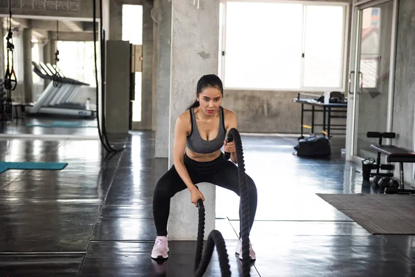 Asian woman battle rope exercise in gym