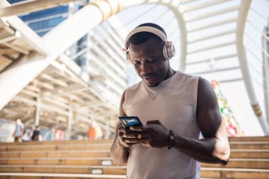 Spor adamı şehirde idmandan sonra akıllı telefon kullanıyor.