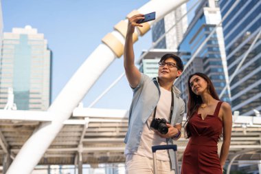 Asyalı turist çift şehirde selfie çekiyor.