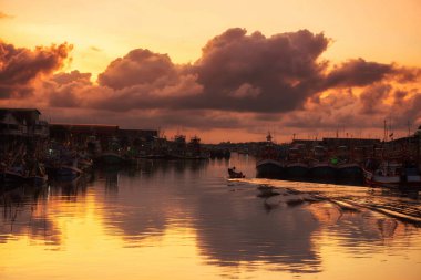 Balıkçı tekneleri gün doğumunda rıhtımdan geçer