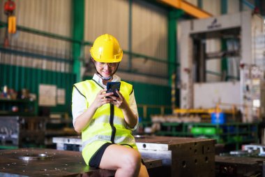 Çalışırken telefon kullanan bir fabrika işçisi.