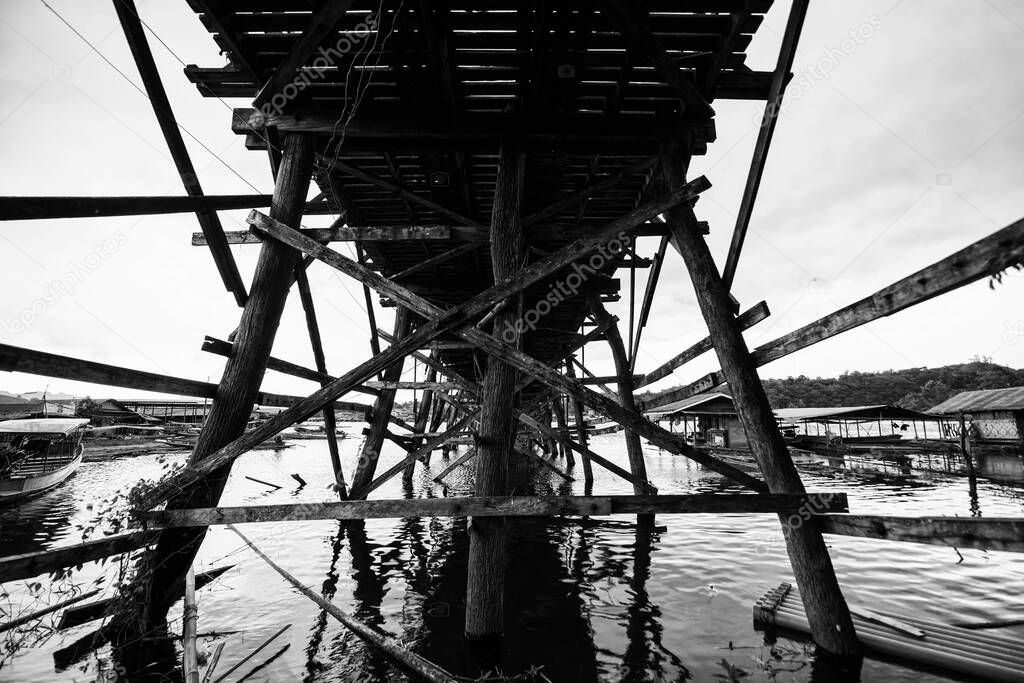 Mon wooden bridge by ant eye view and Traditional wooden floating house at Song Kalia river in Sangkhlaburi, Kanchanauri, Thailand. Travel destination landmark with black and white color process.