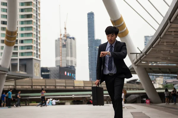 不安アジアの中国のビジネスマンが実行し ラッシュ時に街の散歩の時間を確認するために時計を見てください 電車の輸送 会議のために若い男が遅れて急いでください 事務所生活及び業務競争 — ストック写真