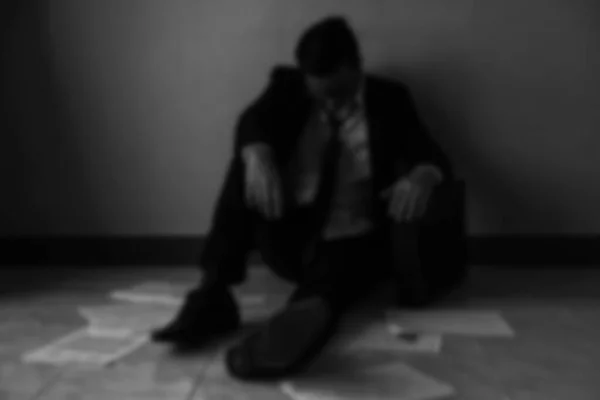 Blurred abstract of sad businessman get fired from work due to COVID-19 or corona-virus impact with copy space. Global business impact from pandemic virus claimed by WHO. black and white process.