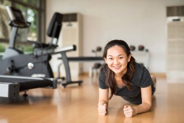 Spor salonunda sabahları idman yaptıktan sonra yere ince gövdeli mutlu, genç Asyalı bir kadının portresi Çinli kız iyi sağlık, motivasyon ve çalışma tarzı konsepti için egzersiz yapıyor..