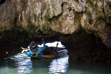 Tayland 'ın Phang Nga Körfezi' ndeki lagün ve mangrov ağacı bataklığını ziyaret etmek için küçük mağaralarda kano ile uzanan turist ve denizci. Tayland 'ın güneyindeki ünlü tatil beldesi.