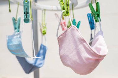 Güneşli bir günde asılarak mor ötesi güneş ışığıyla koronavirüsü yok etmek için pembe kumaş maske yıkama ve kurutma. Küresel tedarik eksikliği nedeniyle kovid-19 hastalığını önlemek için nesneyi tekrar kullanın. Karantina, sosyal uzaklık