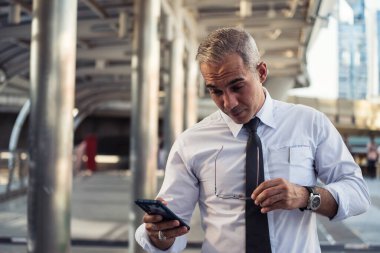 40-50 yaşları arasında şokta olan işadamı, kovid-19 veya koronavirüs hastalığının etkisini azaltmak için şirket kötü haberlerini akıllı telefondan okudu. Ücretsiz ayrılma, işsizlik, evden çalışma.